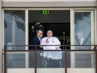 Man in white robe waving to crowd