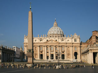 St. Peter's Basilica with a tall obelisk in front under a clear blue sky. Tourists gather in the square, capturing a historic and serene scene.