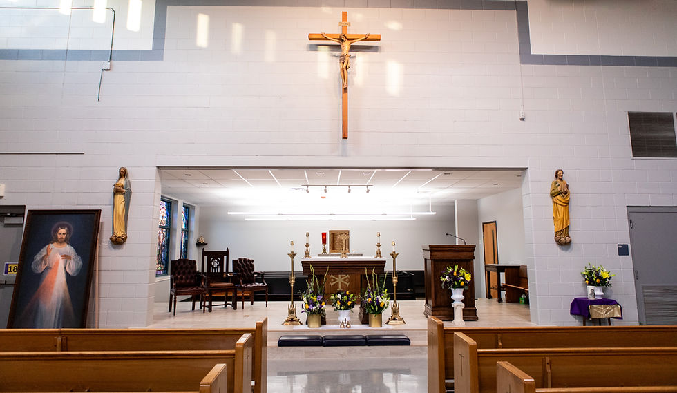 Church interior with altar, cross and religious statues. Bright lighting, floral decorations, wooden pews, and a serene atmosphere.