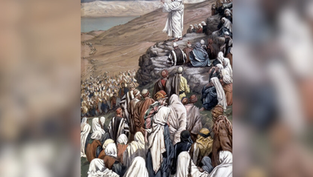 A figure dressed in white speaks to a large crowd on a hillside. People wear robes in earth tones. The mood is attentive and reverent.