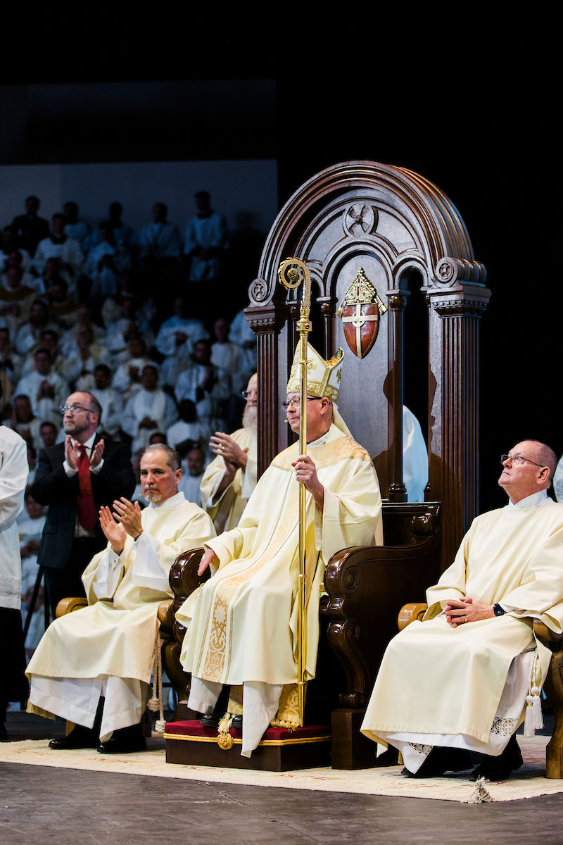 A bishop sits on the cathedra, holding his crozier, during the liturgy.