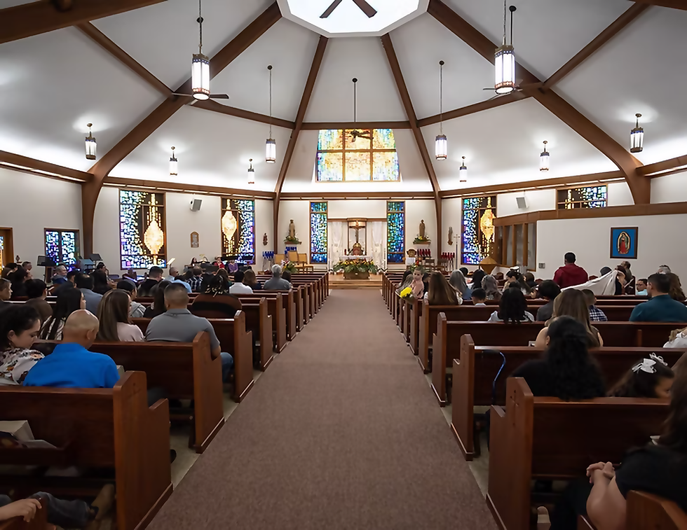 People seated in a church with stained glass windows, wooden pews, and lit chandeliers. A peaceful and solemn atmosphere.