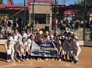 A softball team in white and purple uniforms poses with a "CHSAA State Champions Softball 2025" banner and trophy on a sunlit field.