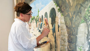 Artist in white shirt paints a detailed fresco of people under arches. Palette with vibrant colors. Focused mood. No visible text.