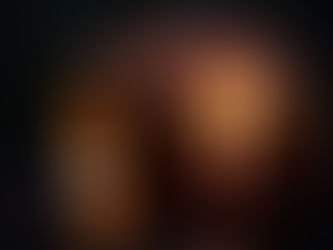Carved pumpkin with a glowing cross cutout, lit by a candle inside. Dark background and wet surface create a moody, atmospheric scene.