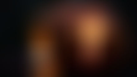 Carved pumpkin with a glowing cross cutout, lit by a candle inside. Dark background and wet surface create a moody, atmospheric scene.