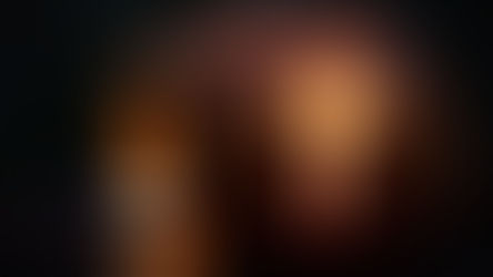 Carved pumpkin with a glowing cross cutout, lit by a candle inside. Dark background and wet surface create a moody, atmospheric scene.