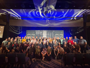 A large group of people pose smiling in front of a stage with "Making Missionary Disciples" text, under dynamic blue and white lighting.