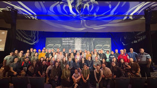A large group of people pose smiling in front of a stage with "Making Missionary Disciples" text, under dynamic blue and white lighting.