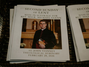 Mass program featuring a priest in black robes, gold church altar in background. Text: Second Sunday of Lent, Feb 28, 2026.