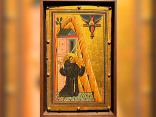 Monk kneels beside building, gazing at six-winged seraph on the cross. Icon has vibrant gold, orange, and black hues. Spiritual aura.