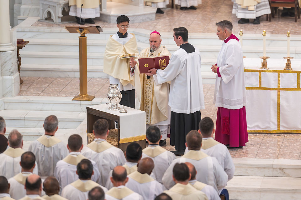 Clergy perform a ceremony in a church. One holds a book while another gestures. Gold-trimmed altar and candles visible. solemn atmosphere.