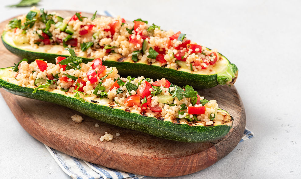 Two stuffed zucchini boats filled with quinoa, spinach, and sun-dried tomatoes, topped with a fresh salad for Lent on a white plate.