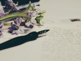 Purple flowers and a fountain pen rest on handwritten letters, evoking a nostalgic and thoughtful mood.
