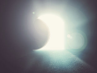 A large, illuminated door opens in a dim space, casting bright light and creating a serene, mystical atmosphere with soft lens flares.