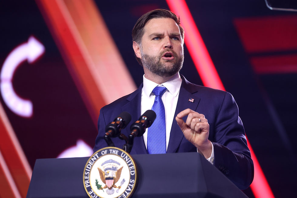 Man in a suit speaks at podium with "Vice President of the United States" seal. Red and orange lights in the background. Determined expression.