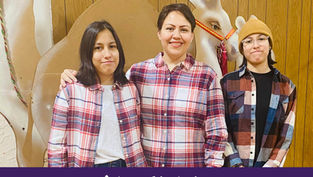 Three people in plaid shirts smile in front of a wooden wall and holiday decor. Text below reads "Appeal in Action" on a purple banner.