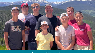 A group of eight smiling people outdoors with snowy mountains in the background. Text on shirts and "Appeal in Action" on the image.