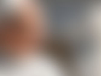 Smiling pope in white robes and skullcap, seen in profile against a blurred gray background, sunlit and peaceful