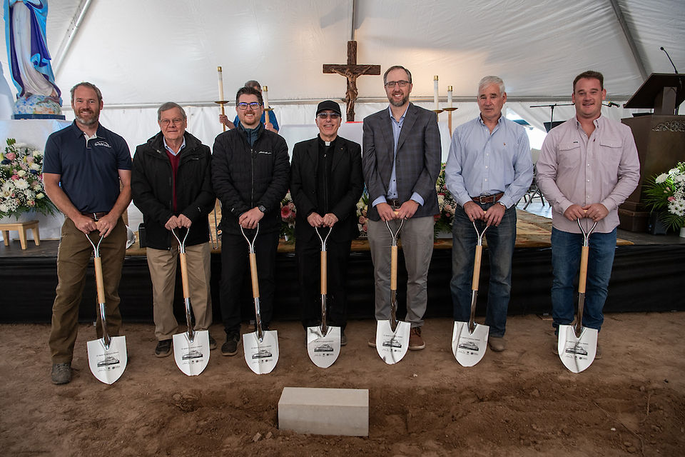 Men holding ceremonial shovels pose together during the church groundbreaking celebration.
