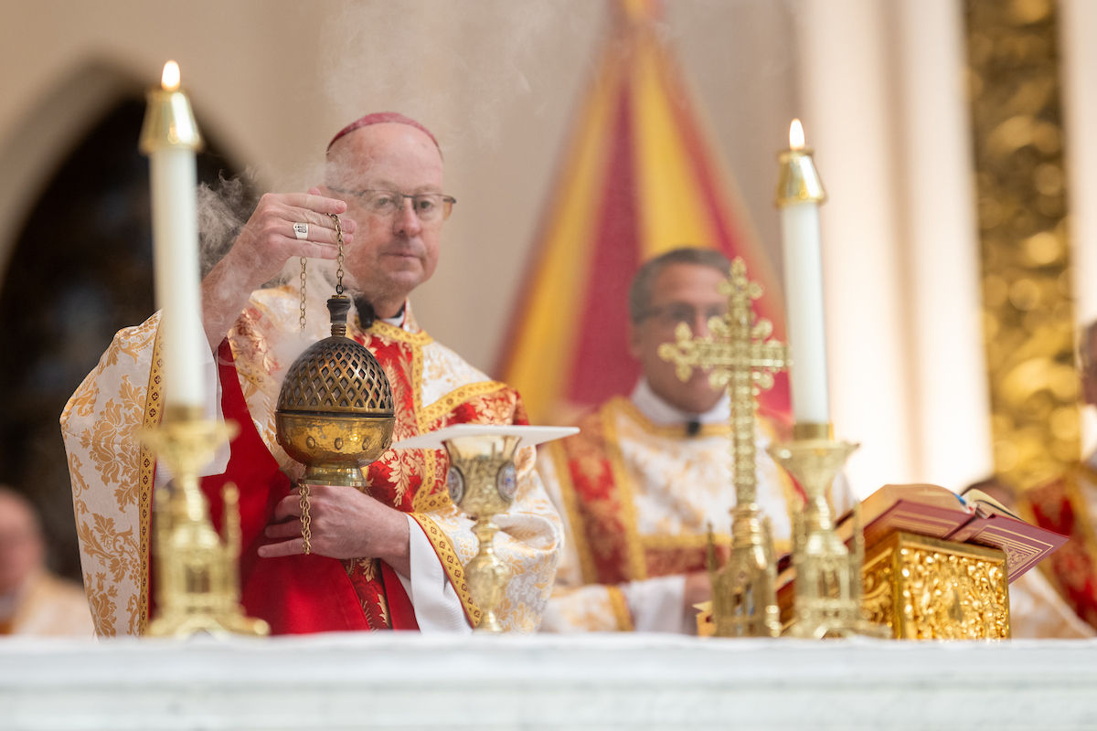 A bishop holds a thurible as incense rises during the liturgy at the altar.