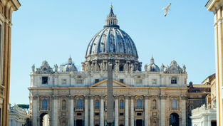 Majestic cathedral with a large dome under a clear blue sky, a seagull flying above. Latin text engraved on the facade. Peaceful mood.