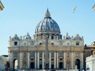 Majestic cathedral with a large dome under a clear blue sky, a seagull flying above. Latin text engraved on the facade. Peaceful mood.