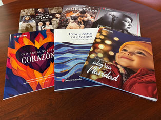A collection of colorful magazines with various texts and images, including a smiling child, on a wooden table. Themes include faith and Christmas.