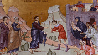 Ancient mural depicting a haloed figure extending a hand to a man in red. Others watch nearby. Text in Cyrillic above. Earthy tones.