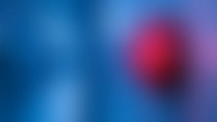 Red alarm light on a blue wall in a corridor, glowing brightly. The background is blurred, creating a tense, urgent mood.