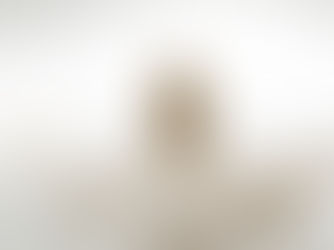 Man with open arms and a serene smile, wearing a white robe, in a bright, soft-focus setting. Peaceful and inviting mood.