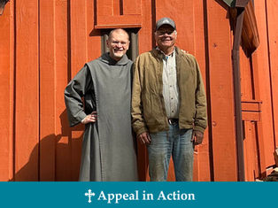 Two smiling men pose in front of an orange wooden building. One wears a gray robe, the other a brown jacket. Text: Appeal in Action.