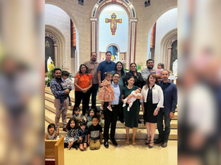 A group of adults and children pose on church steps. The setting is ornate with arches and religious symbols. The mood is joyful and celebratory.