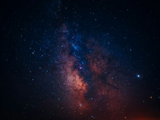 Starry night sky showing the Milky Way with vibrant blues and oranges. Dark, vast setting evokes wonder and serenity. No text visible.