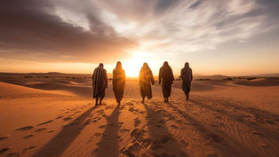 Five cloaked figures walk across desert dunes toward a glowing sunset, their long shadows stretching behind them.