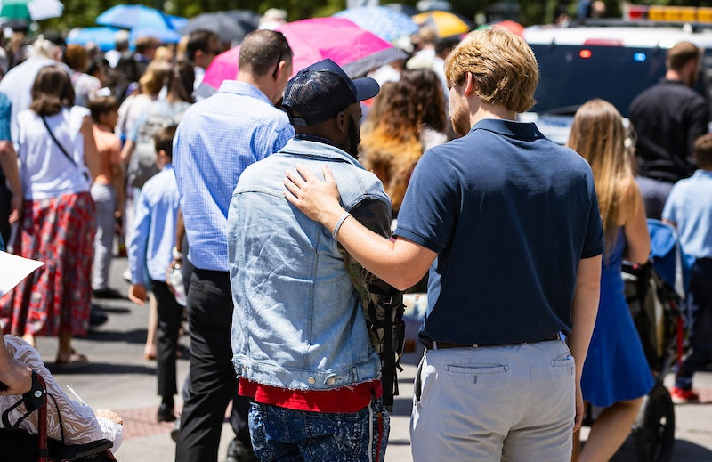 During a Eucharistic procession through Downtown Denver, part of the National Eucharistic Pilgrimage, a young adult stops to encounter a passerby. (Photo by Allison Holdridge)
