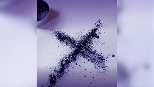 A purple powdery "X" on a white surface, with a metal tin lid nearby. The image has a soft purple gradient, creating a mysterious mood.