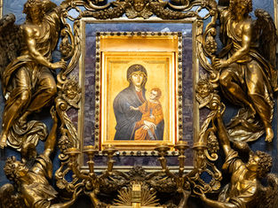 Ornate gold religious altar with angels around a blue-framed Madonna and Child icon, Greek letters visible, solemn and reverent