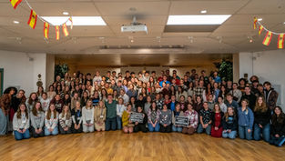 Group of people smiling in a room with wooden floors. Spanish flags hang from ceiling. Two signs read "Abortion Betrays Women" and "The Future is Anti-Abortion".
