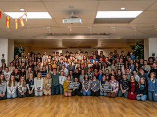 Group of people smiling in a room with wooden floors. Spanish flags hang from ceiling. Two signs read "Abortion Betrays Women" and "The Future is Anti-Abortion".