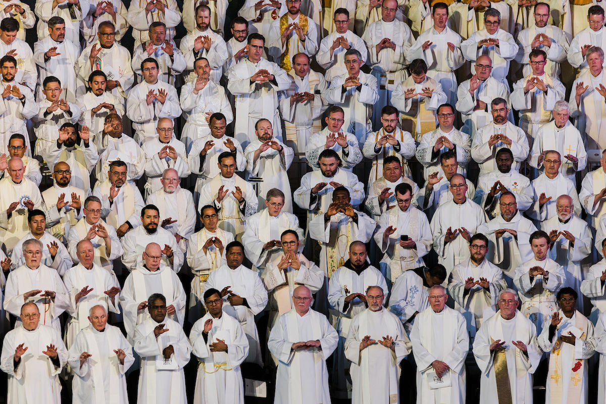 Priests extend their hands in prayer during the consecration.