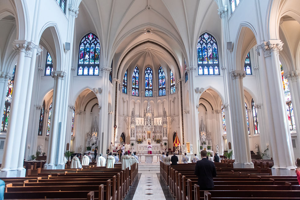 Interior of a grand church with stained glass windows, ornate altar, and people in white robes during a ceremony. The mood is solemn.