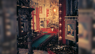 Ornate church interior with a large gathering of people. Red and gold decor dominates. Illuminated altar and religious art visible.