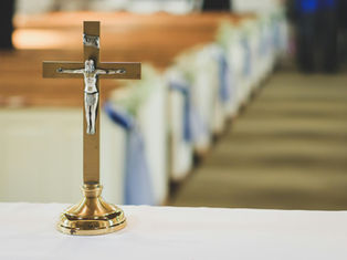 Gold crucifix with silver Jesus figure on an altar, blurred church aisle in the background, evoking a serene and reverent mood.