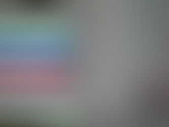 Stack of colorful books with green, blue, red, and yellow spines, against a soft, blurred gray background.