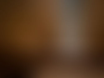 Man seen through a confessional screen in a wooden booth. The setting is dimly lit, conveying a solemn, contemplative mood.