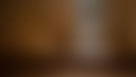 Man seen through a confessional screen in a wooden booth. The setting is dimly lit, conveying a solemn, contemplative mood.