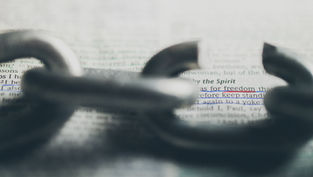 A broken chain lies on a page with highlighted text "for freedom" and "keep stand." The focus is on freedom, evoking a hopeful mood.