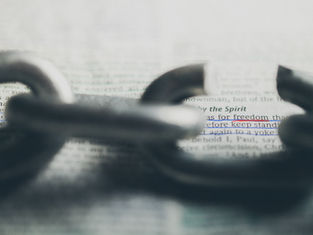 A broken chain lies on a page with highlighted text "for freedom" and "keep stand." The focus is on freedom, evoking a hopeful mood.