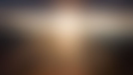 A person stands on a mountain peak at sunset, with sunbeams breaking through clouds. Majestic landscape, warm colors create a serene mood.